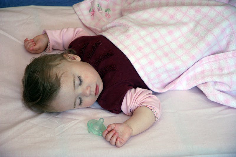 Child sleeping with a pacifier in hand