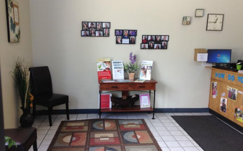 Waiting room with a wooden table, informational brochures, and framed photos on the wall