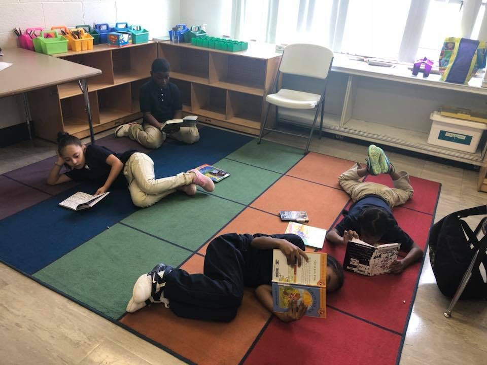 Children reading books on the floor in a classroom