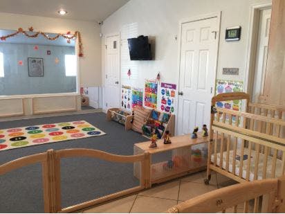 Childcare room with cribs, play area, and educational posters