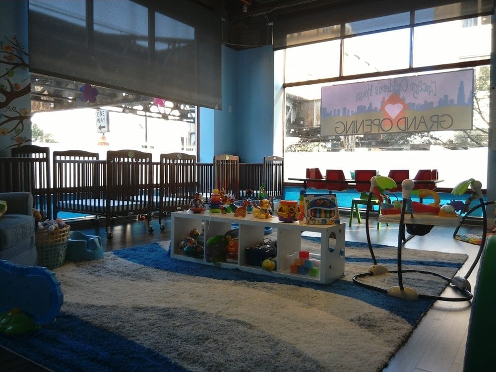 Indoor play area with cribs, toys, and a baby swing