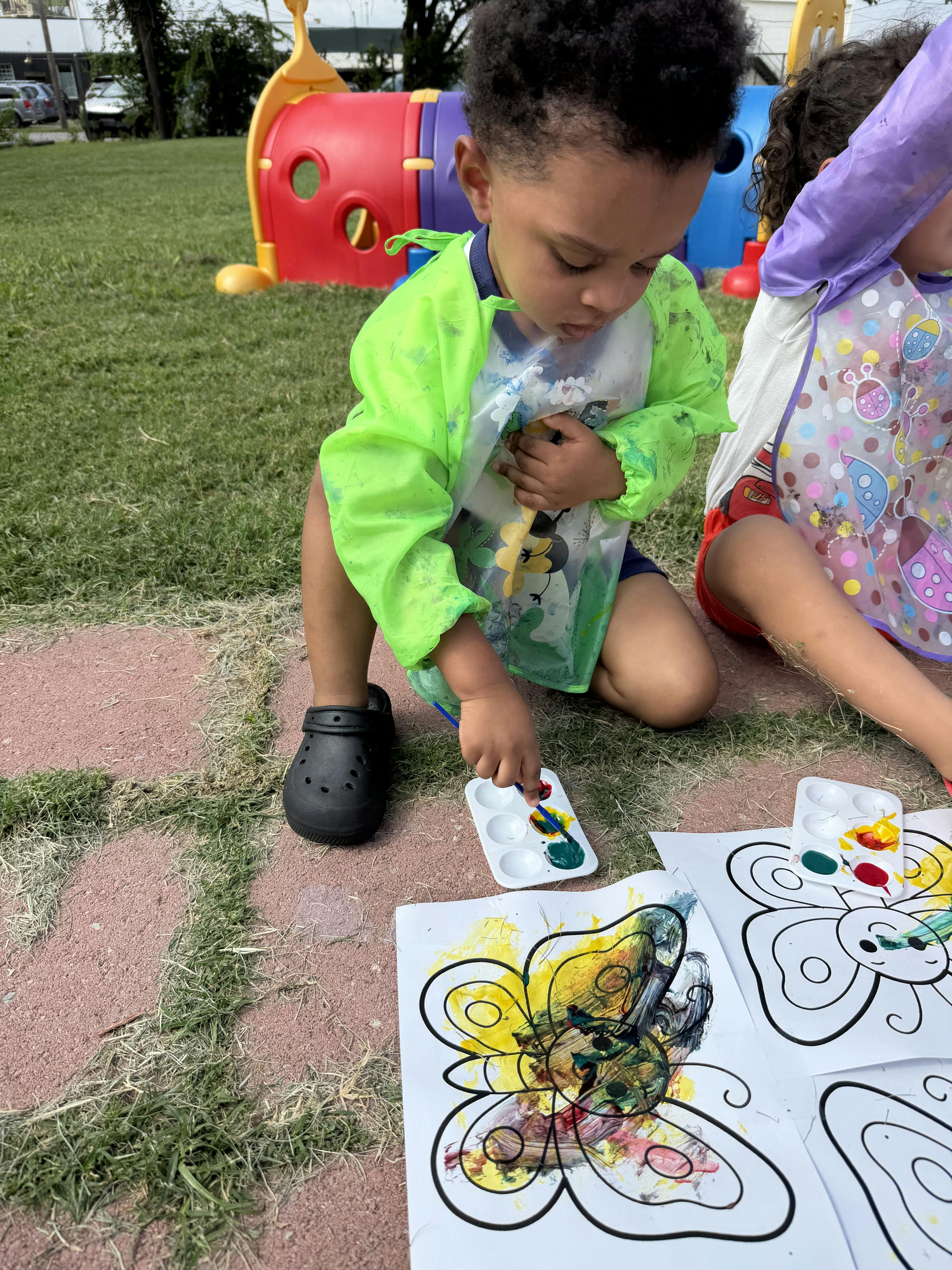 Child painting a butterfly drawing outdoors