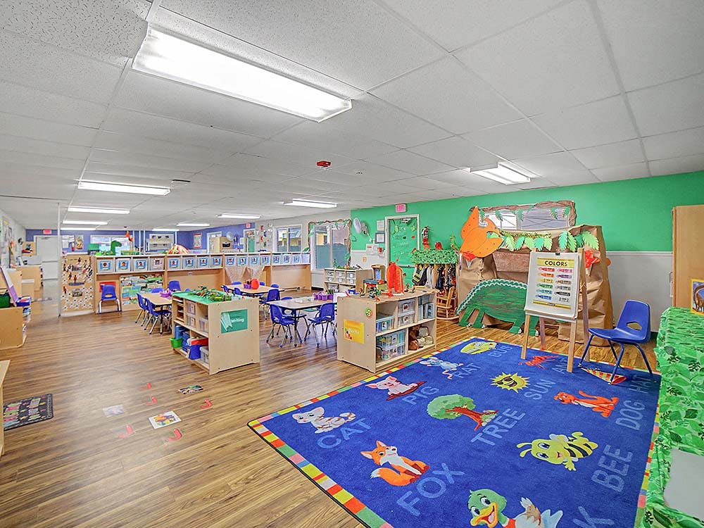 Classroom with tables, chairs, and a colorful rug