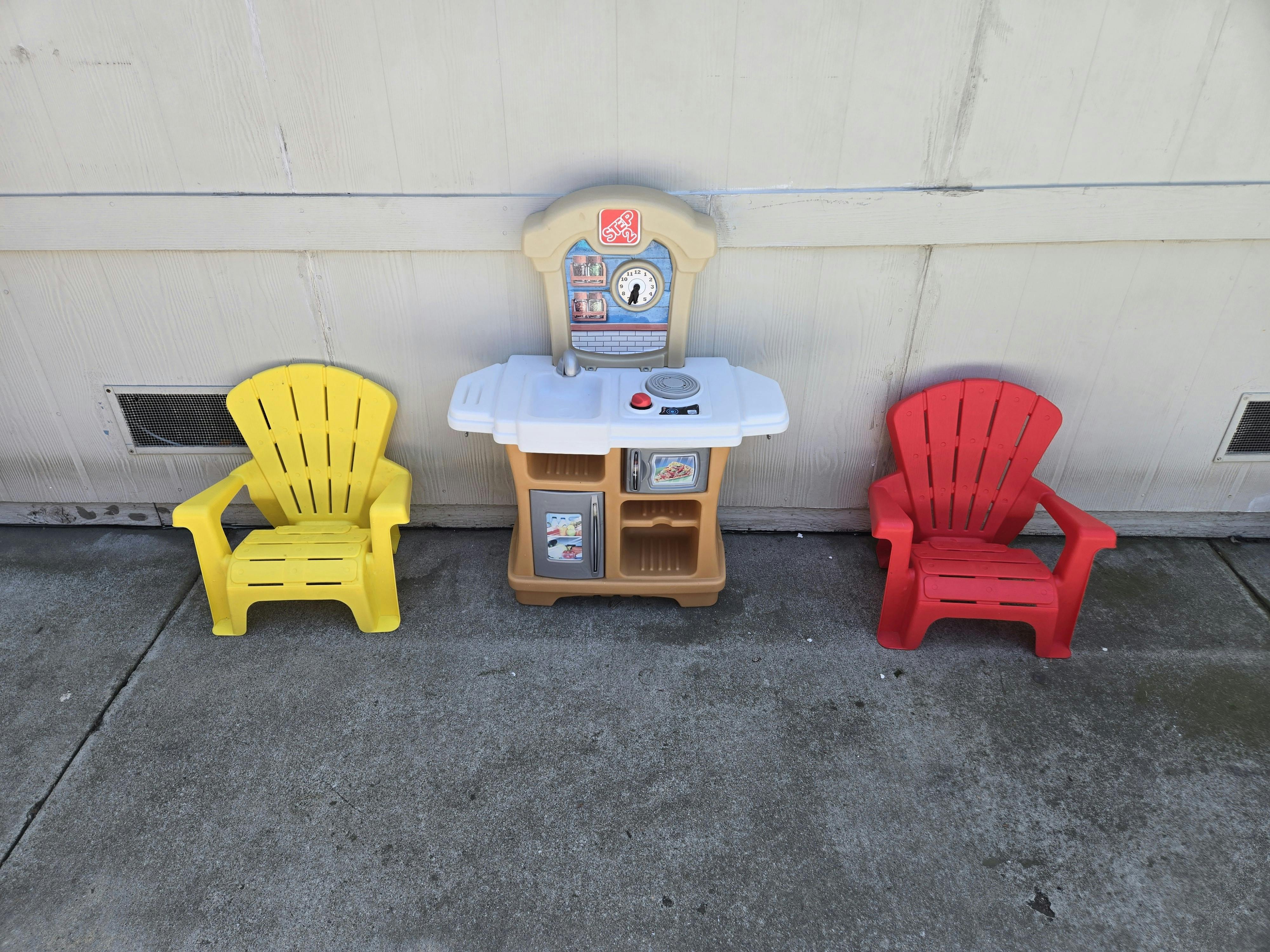 Two child-sized chairs and a toy kitchen set