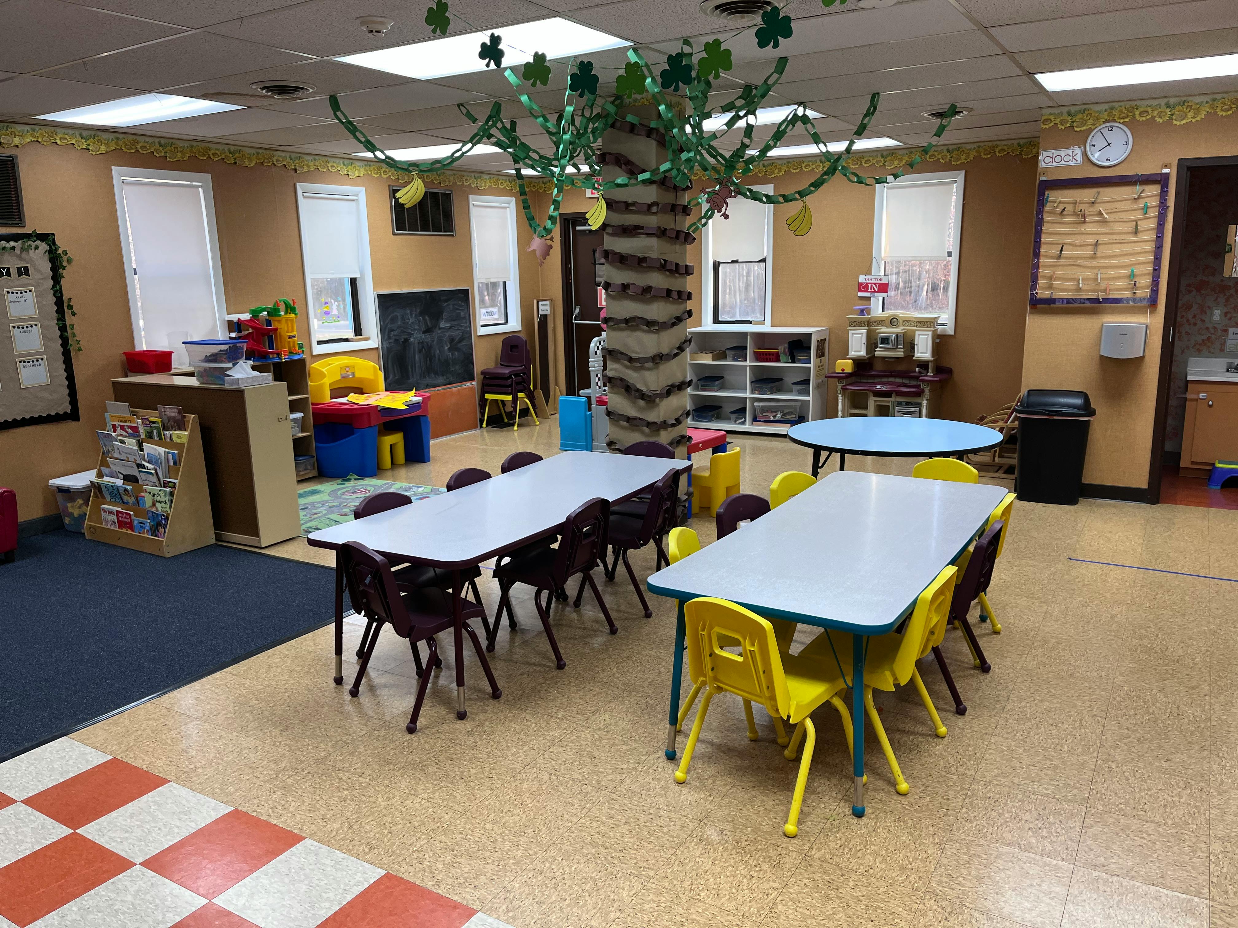 Classroom with small tables and chairs, a tree decoration in the center