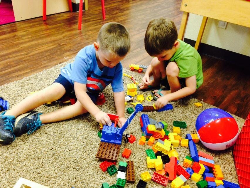 Two children playing with colorful building blocks on a rug