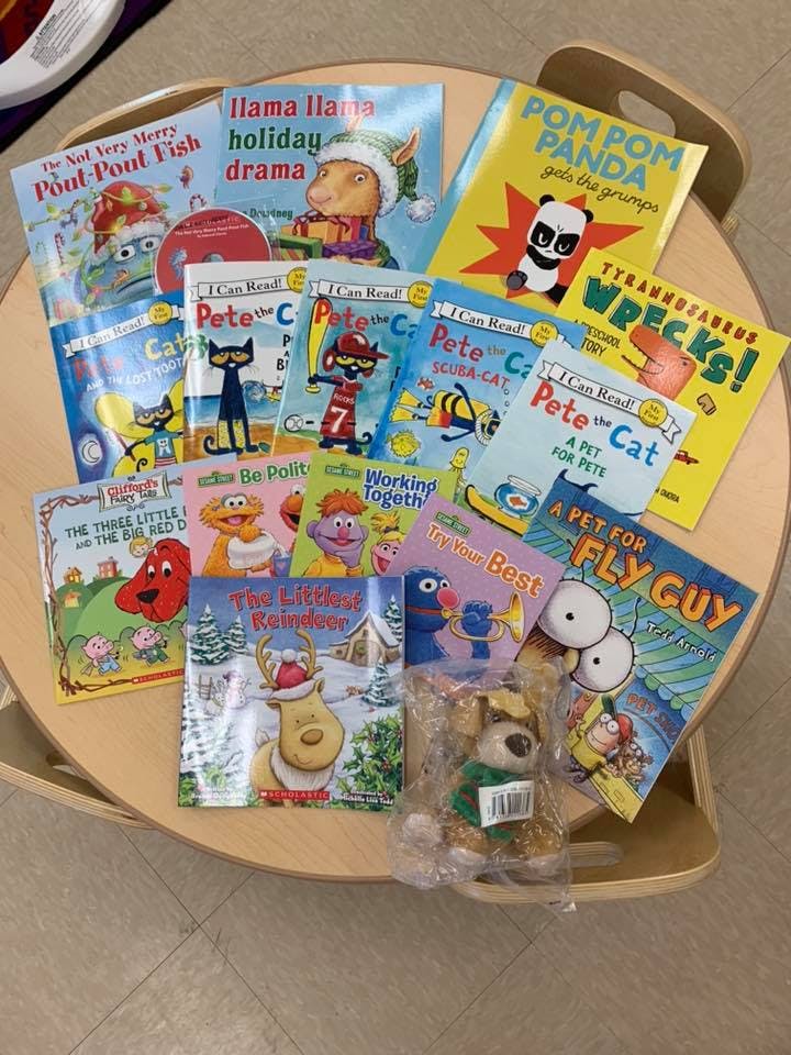 Children's books with various characters and a small stuffed animal