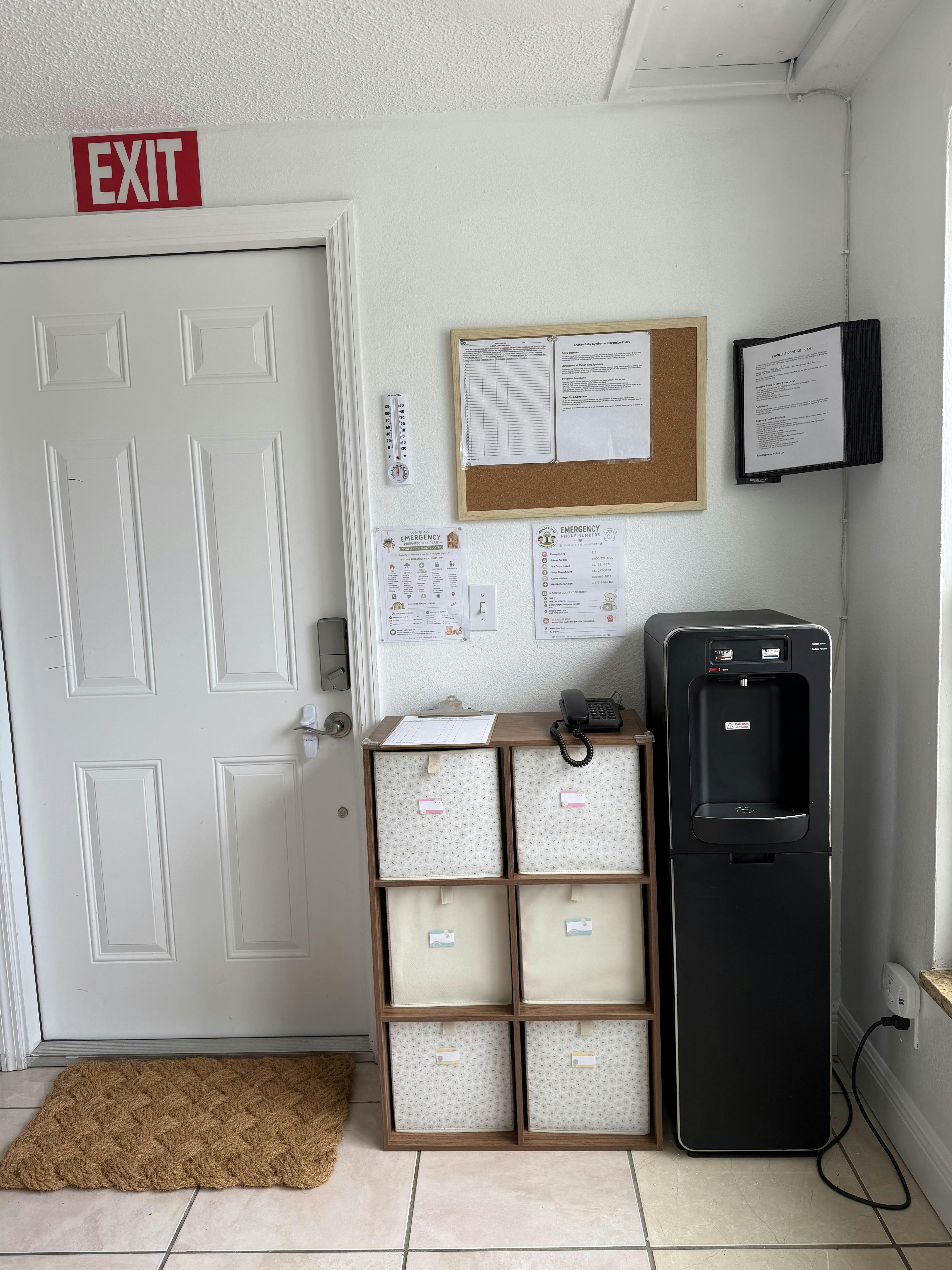 Water cooler and storage unit near an exit door with posted safety documents