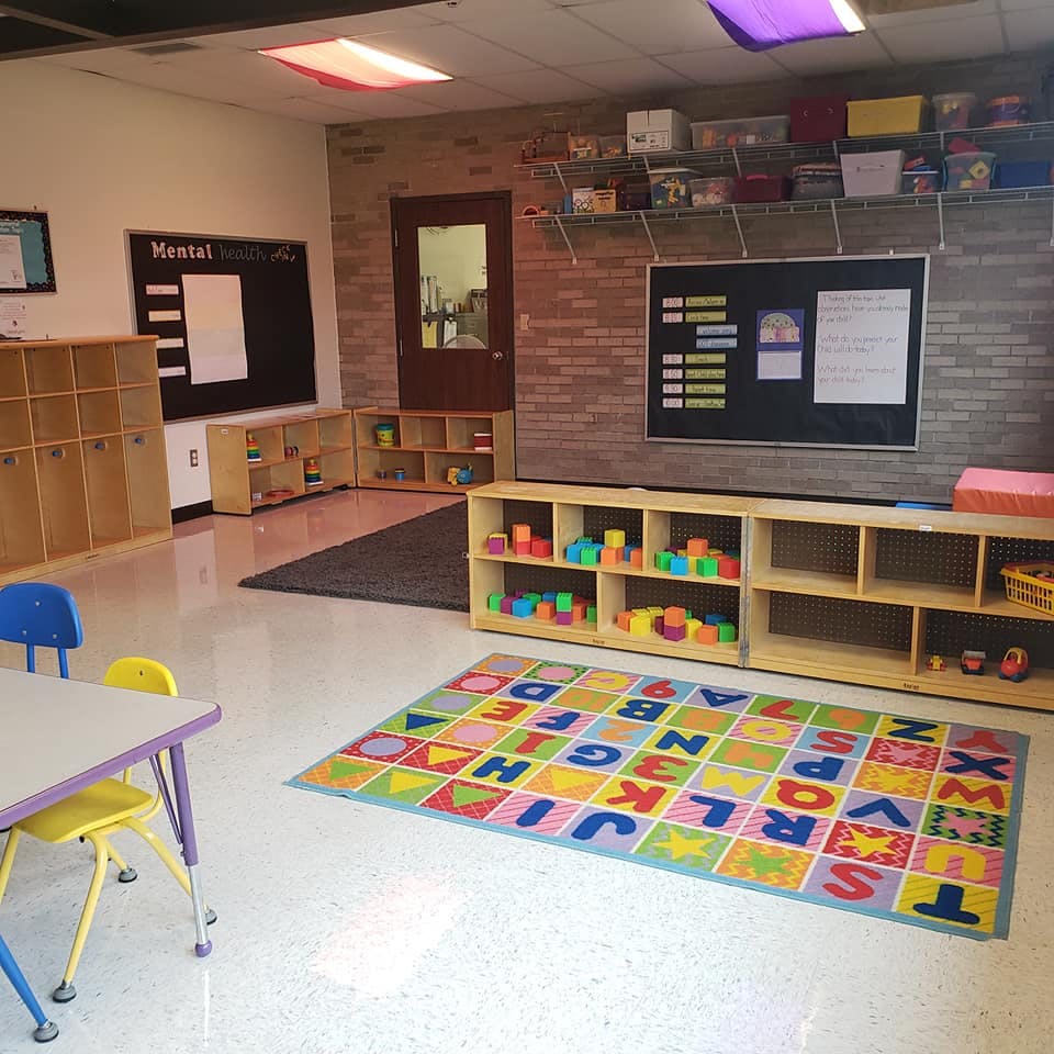 Empty classroom with alphabet rug and shelves of shelves with toys