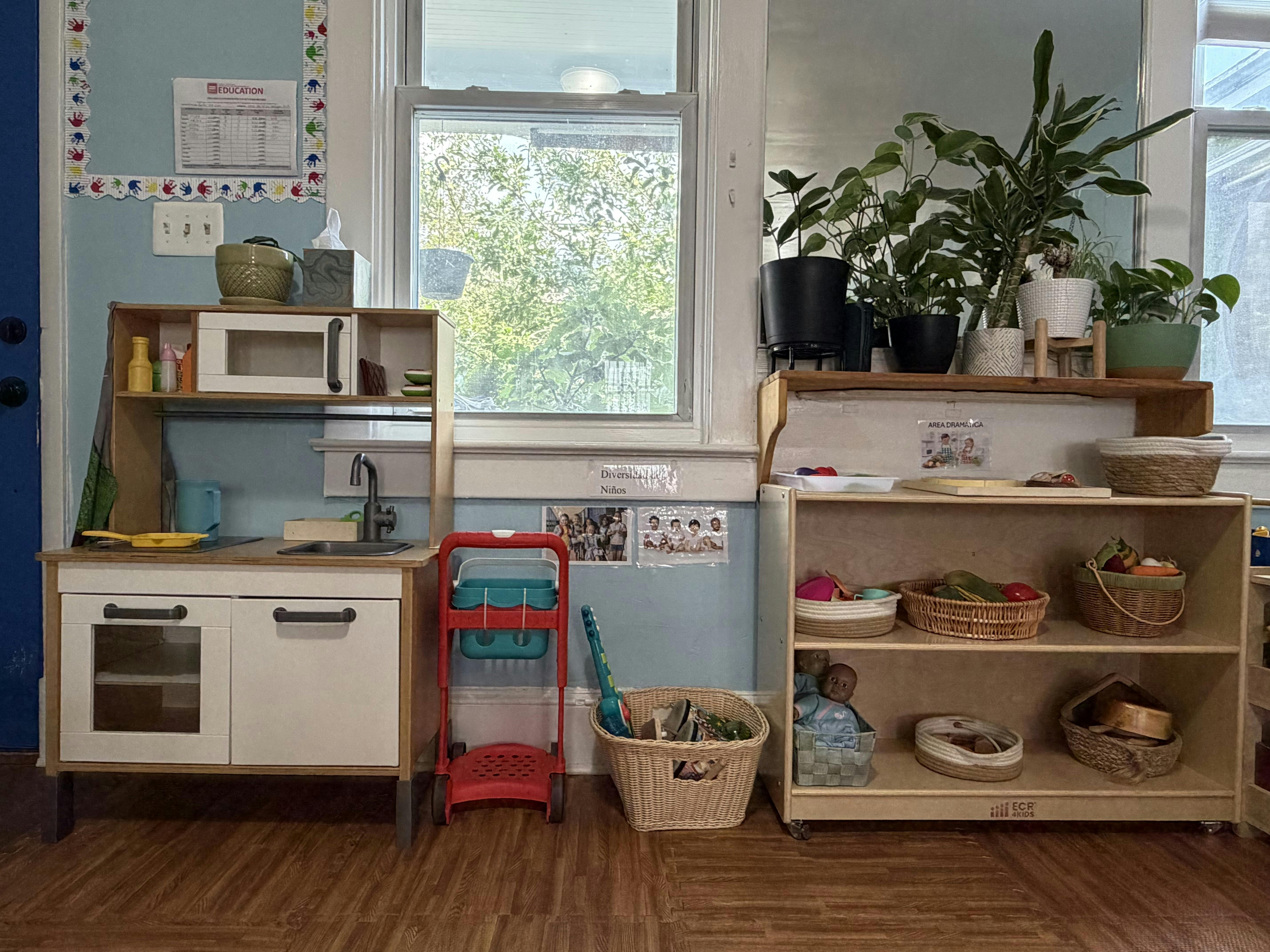 Play kitchen and wooden shelving unit with toys in a classroom