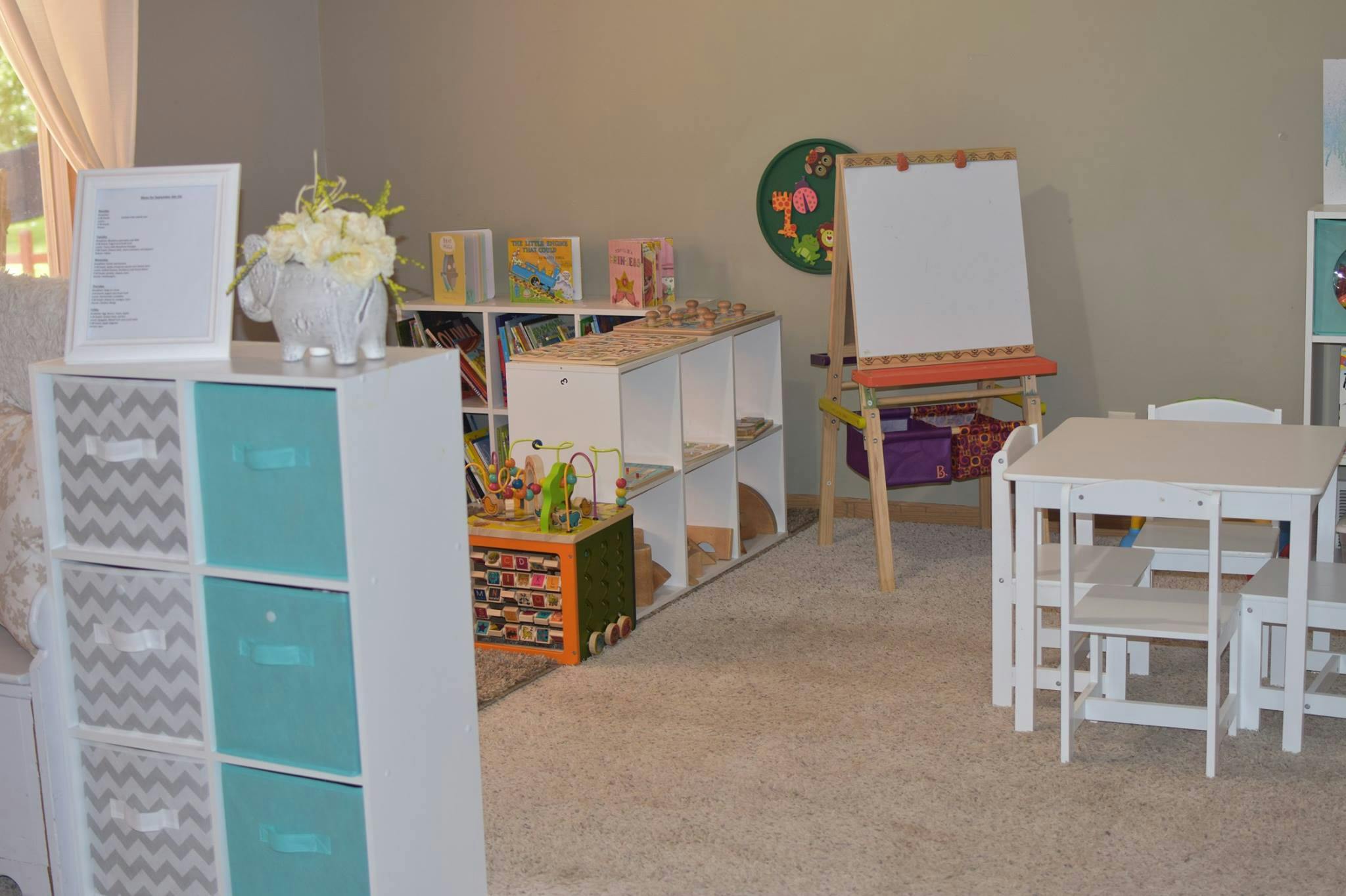 Children's play area with small tables and chairs, storage units, and an easel