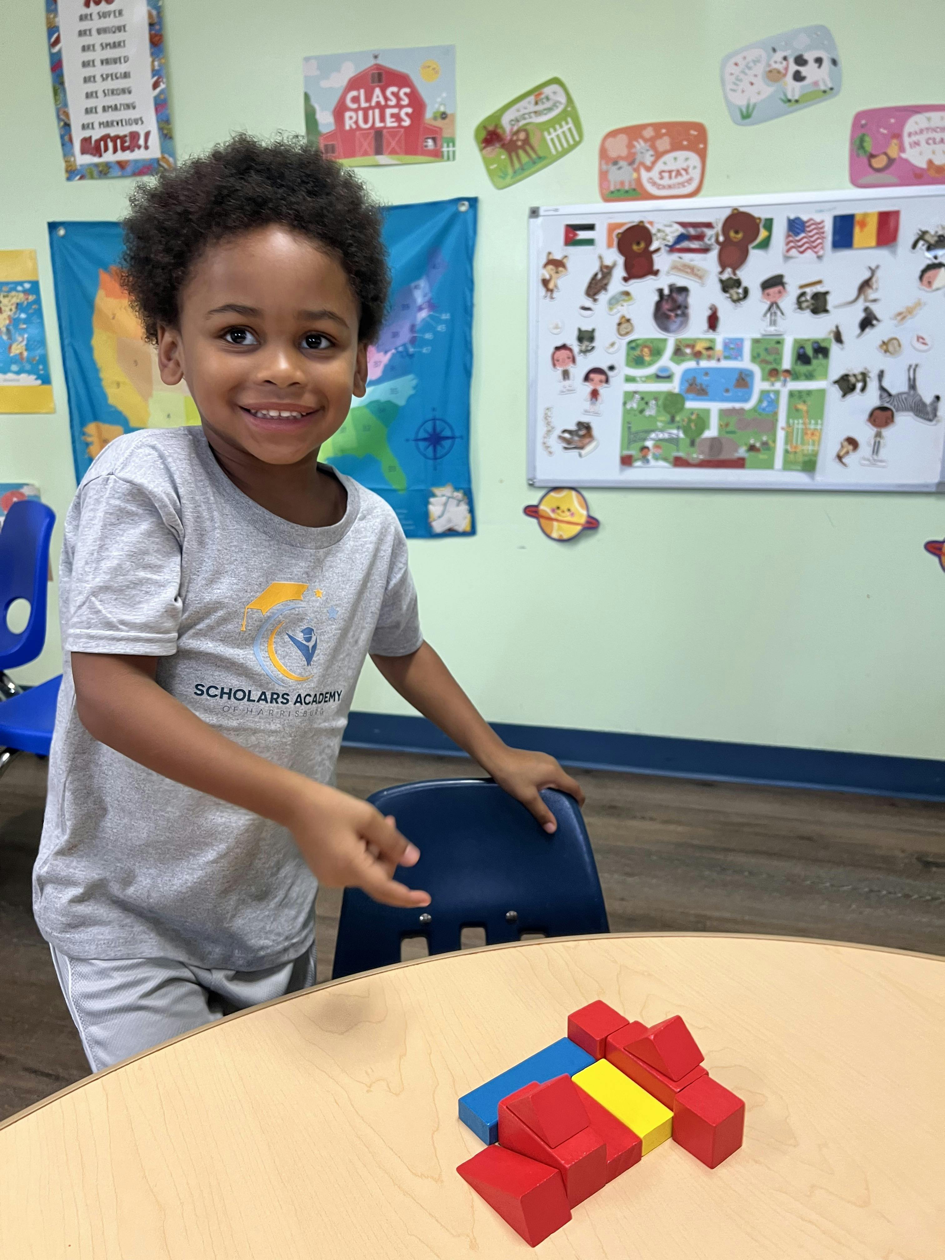 Child smiling in a classroom with wooden blocks on a table