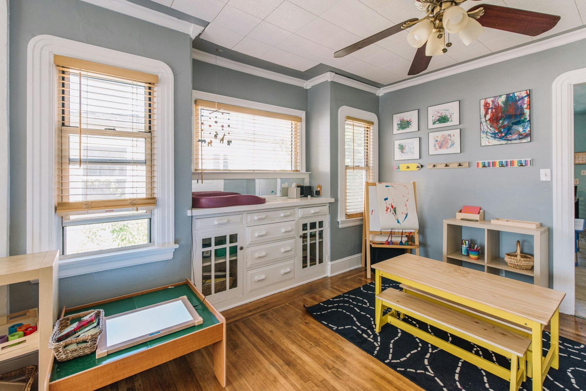 Room with a changing table, easel, and small table with benches