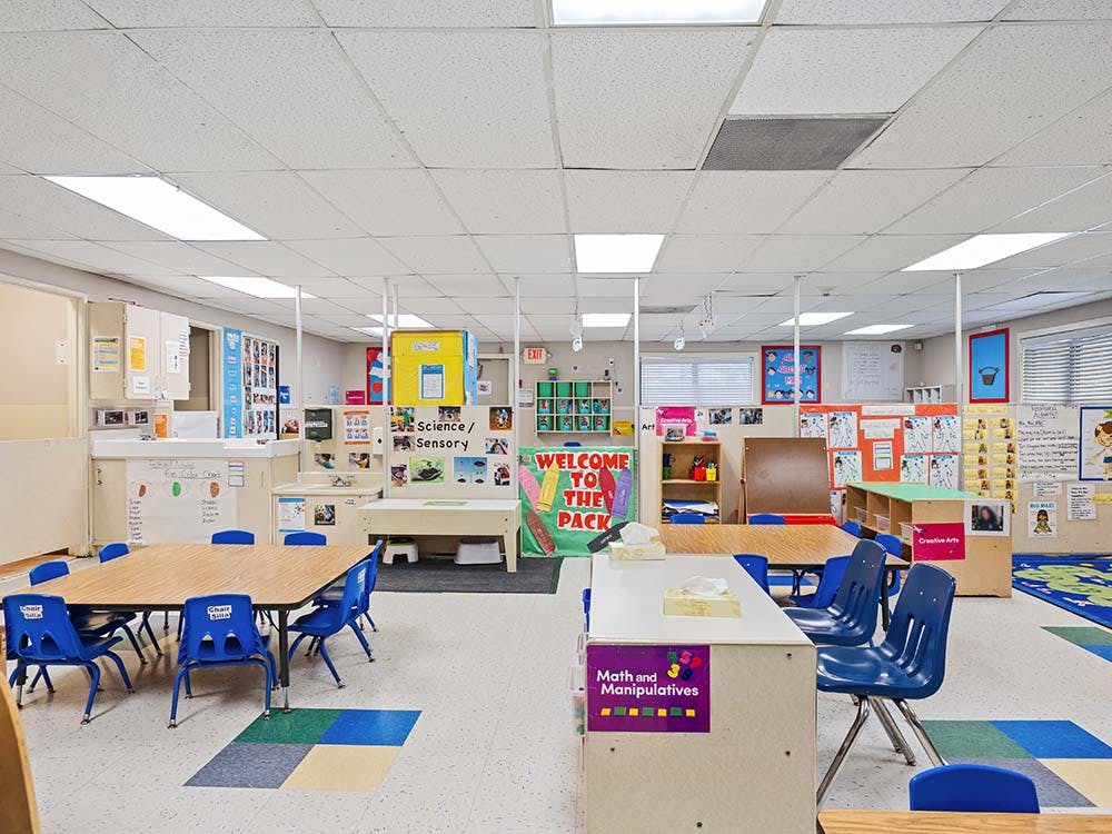 Empty classroom with small tables and chairs, and learning stations
