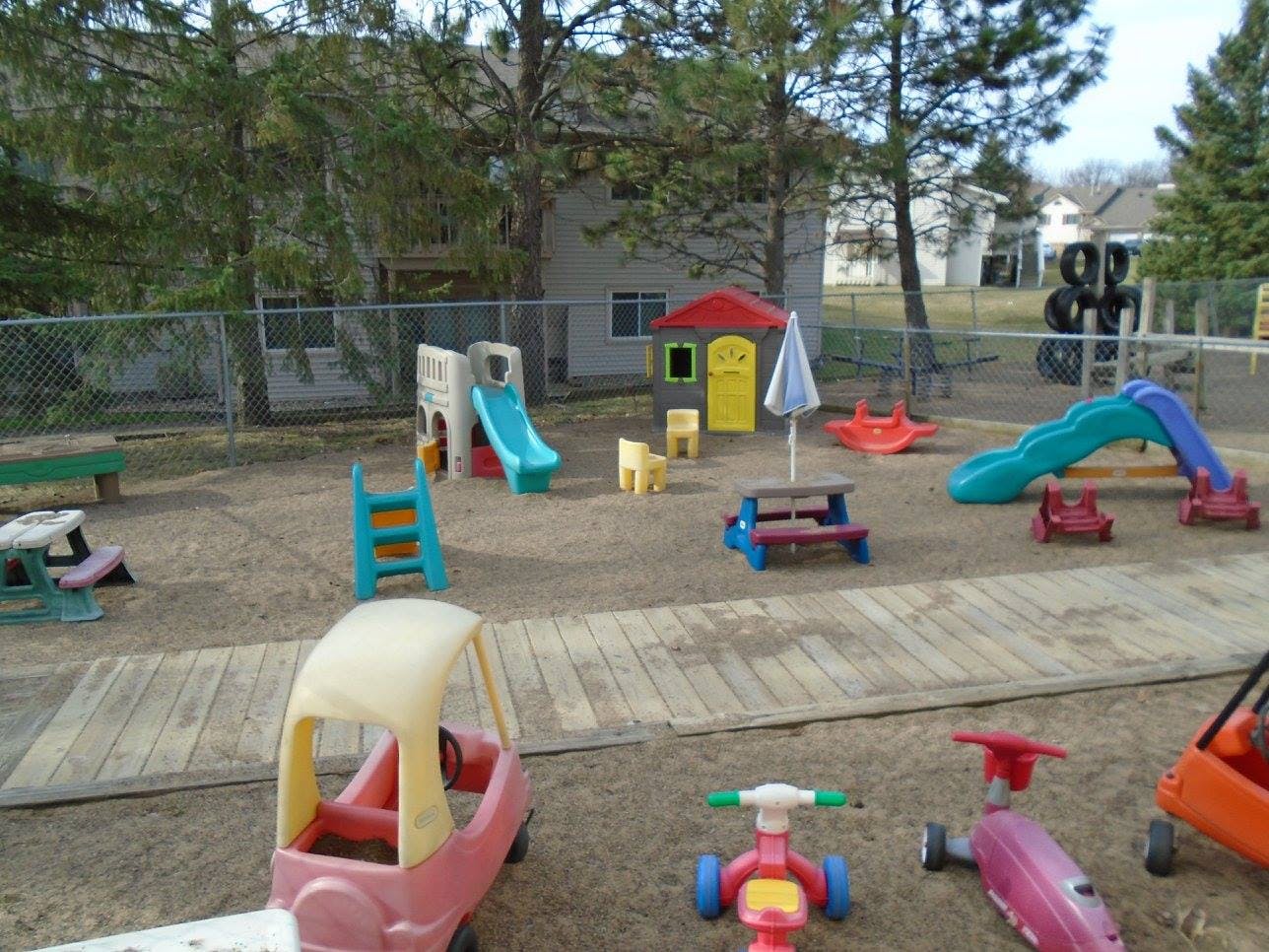 Outdoor playground with slides, playhouses, and ride-on toys