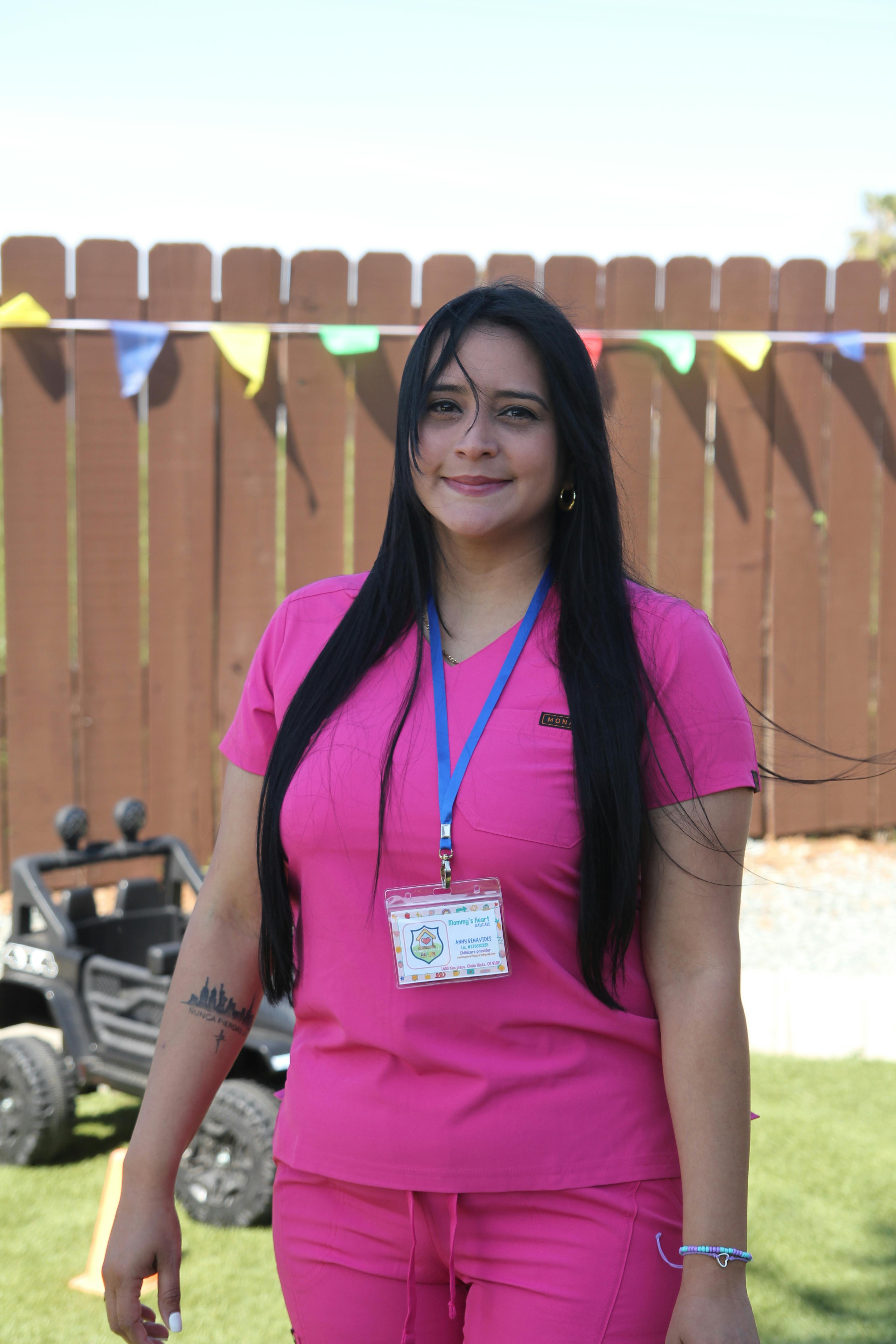 Person in pink scrubs with an ID badge