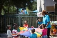Adult and children playing with a colorful parachute outdoors