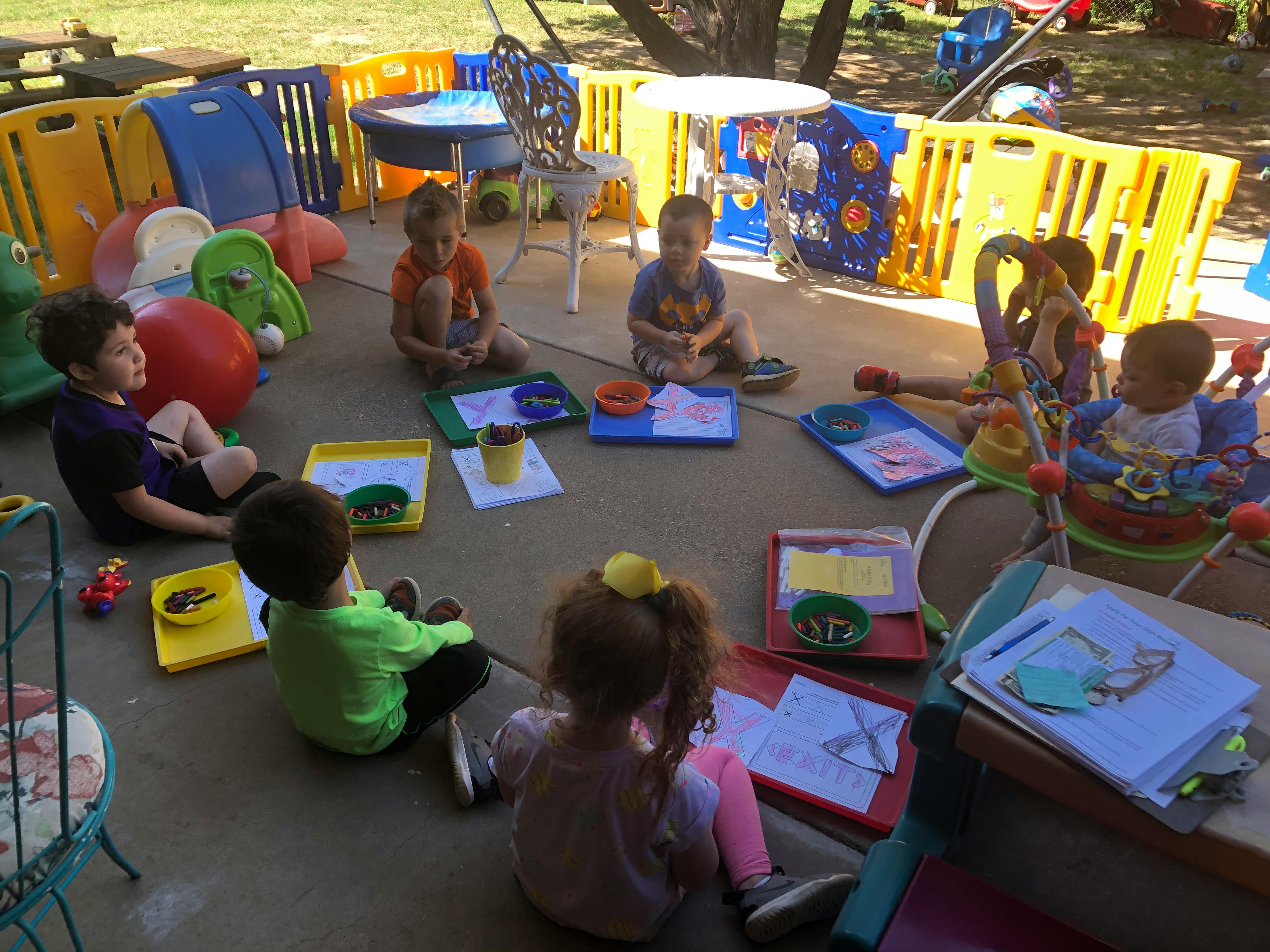 Children sitting on the ground in a circle with activities