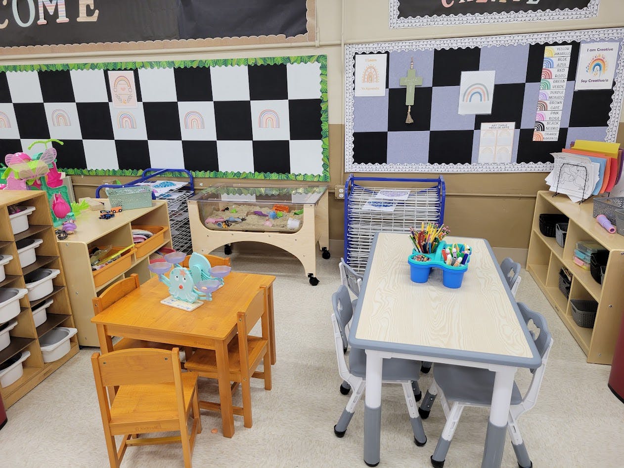 Classroom with child-sized tables and chairs, art supplies, and bulletin boards