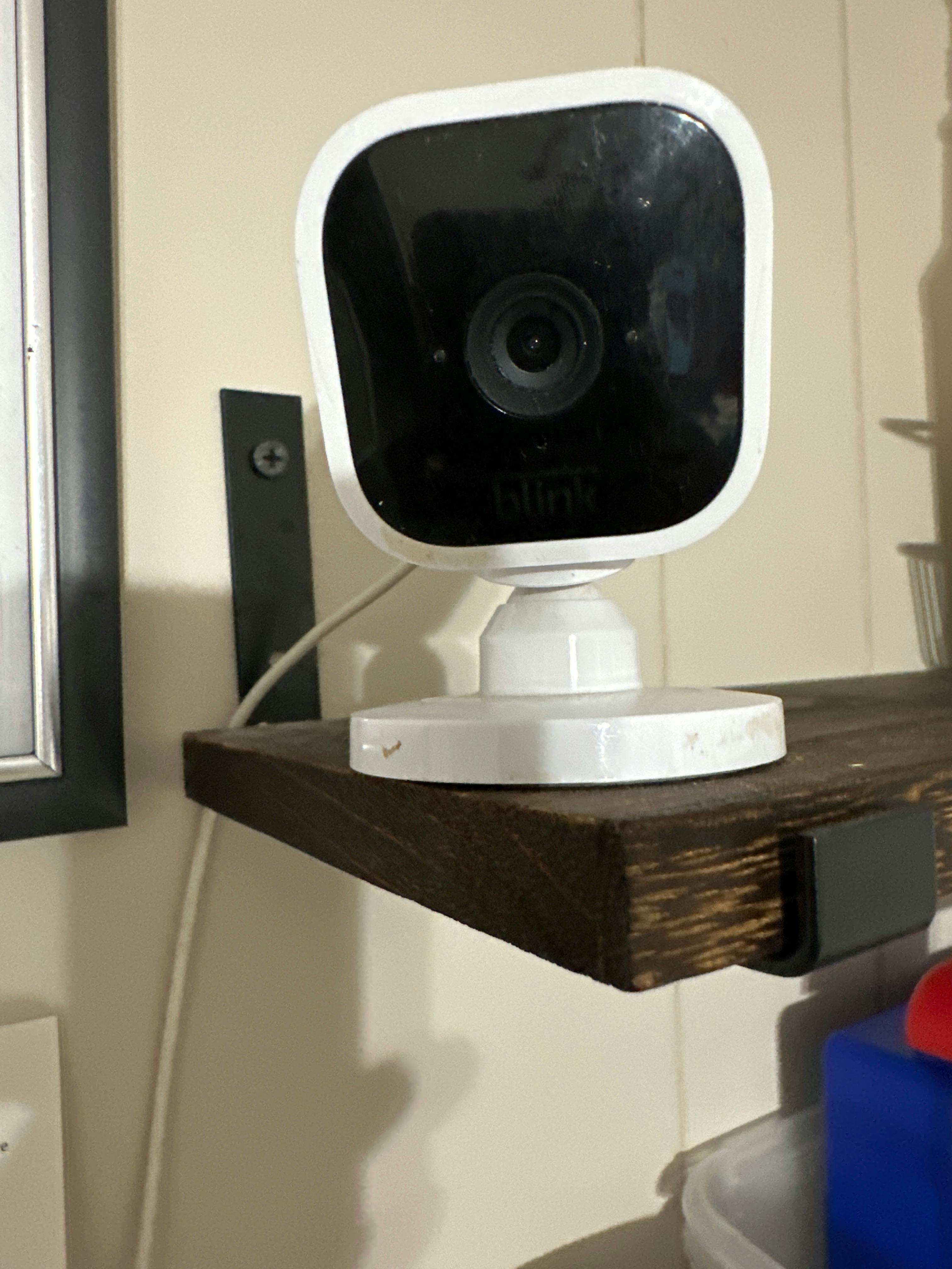 White security camera on a wooden shelf