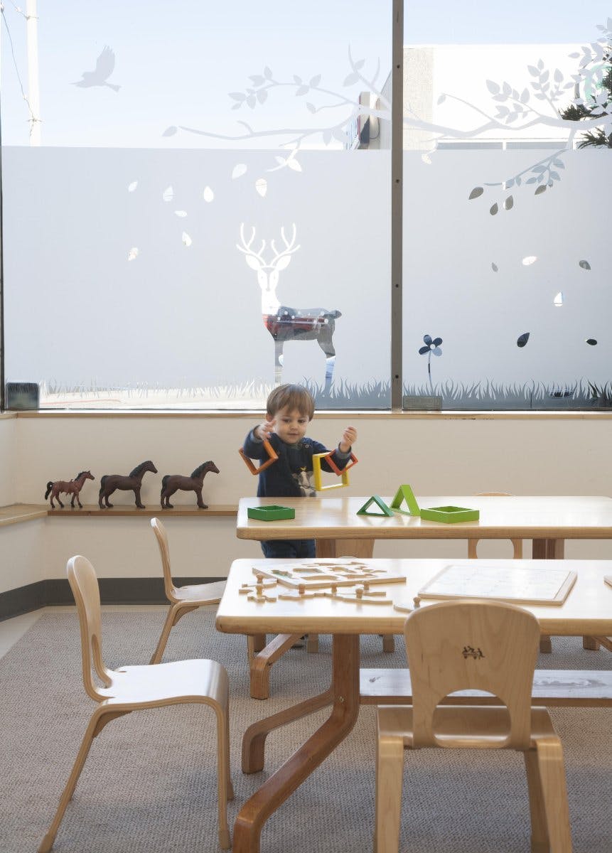 Child playing with building blocks at a table in a classroom