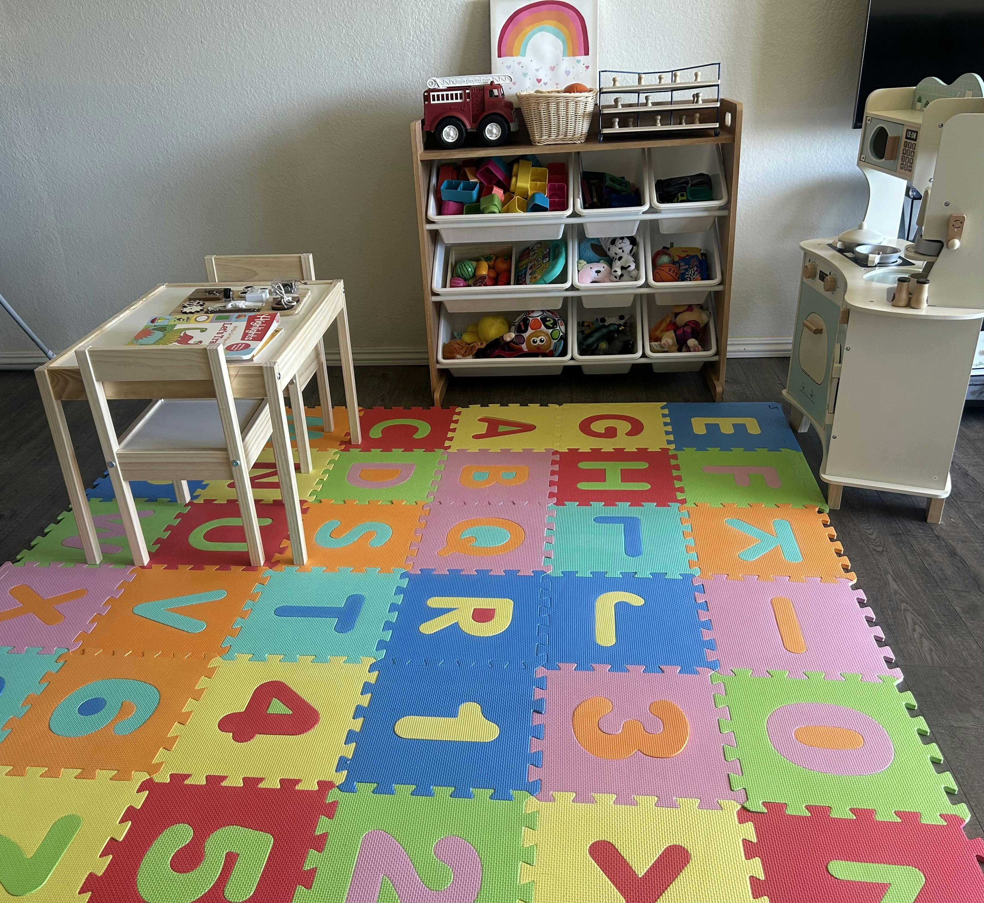 Playroom with colorful alphabet and number floor mats, toy storage, and small table