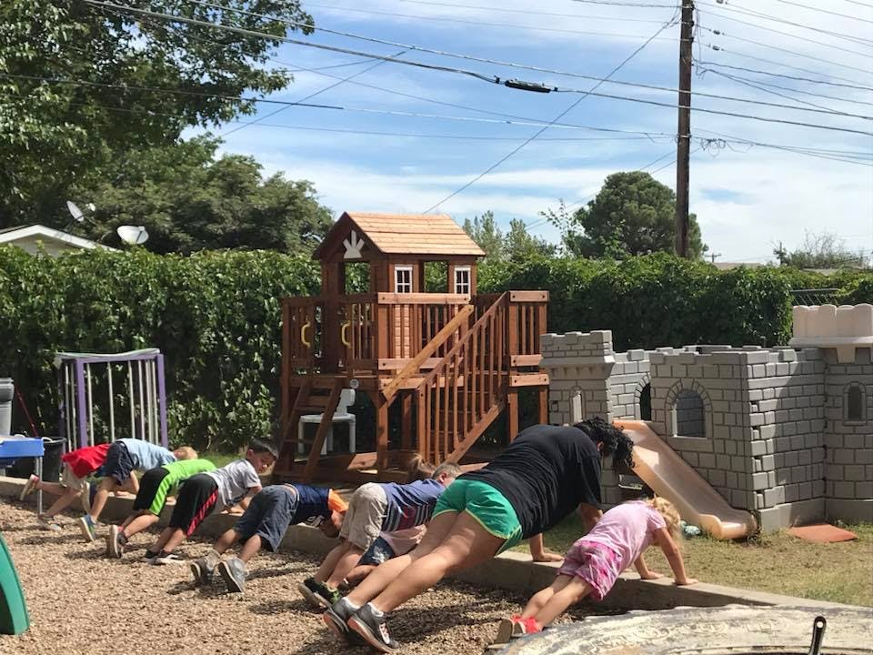 People doing push-ups outdoors near a playground