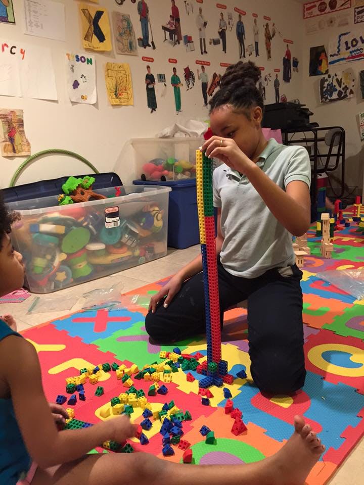 Two children playing with colorful building blocks on a mat