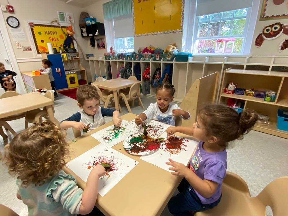 Children painting at a table in a classroom