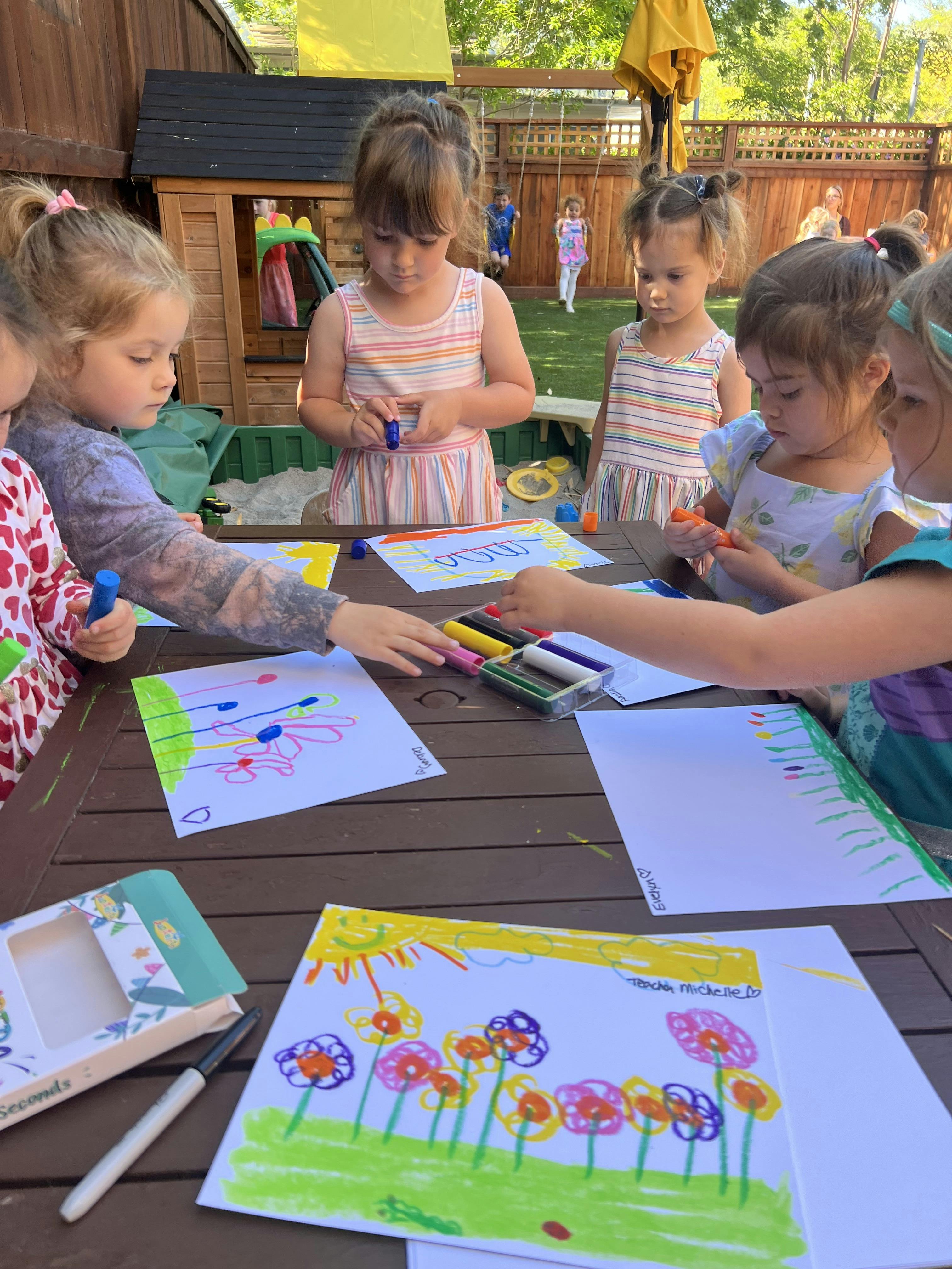 Children drawing at a table outdoors