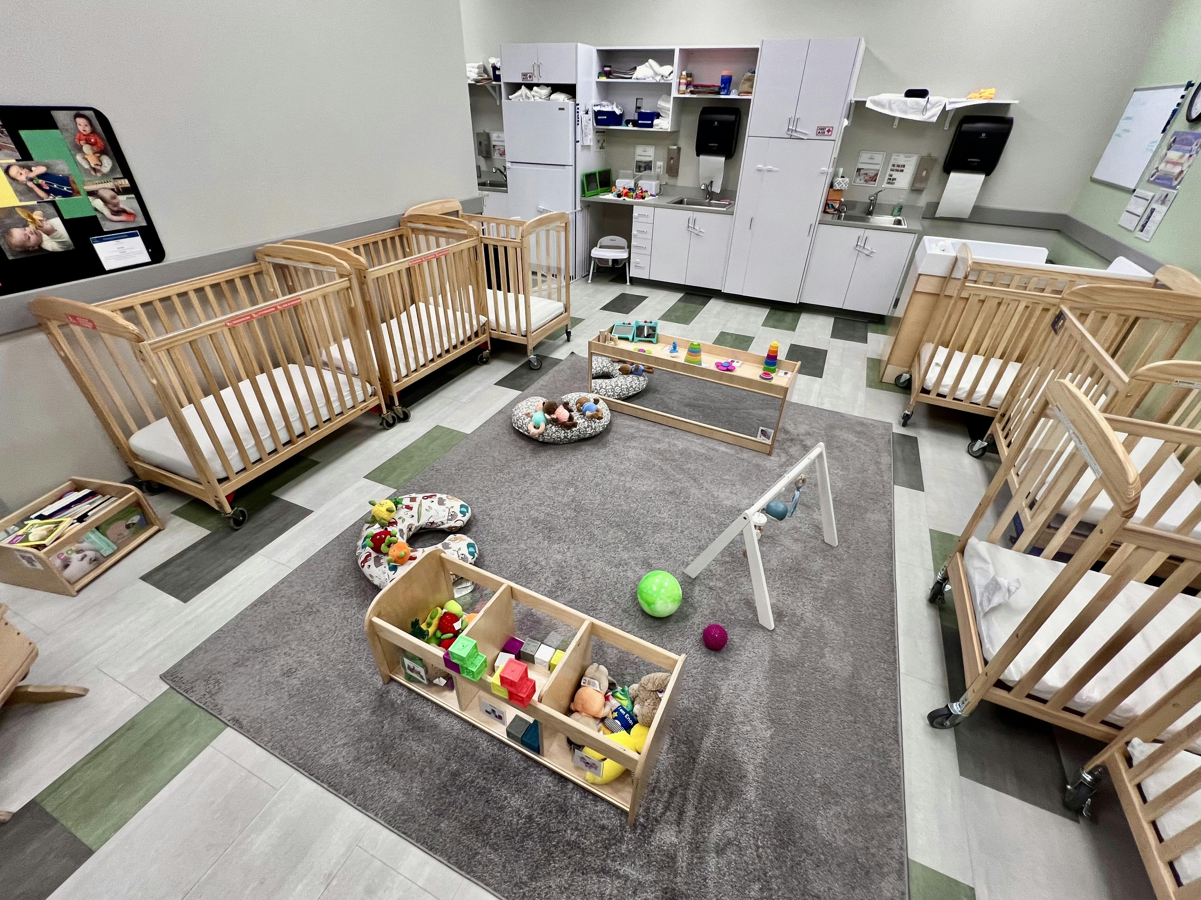 Nursery room with multiple cribs, play mats, and toys