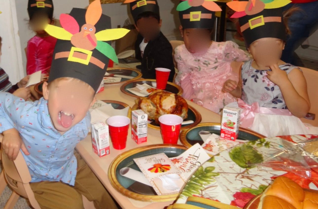 Children wearing pilgrim hats at a table with food