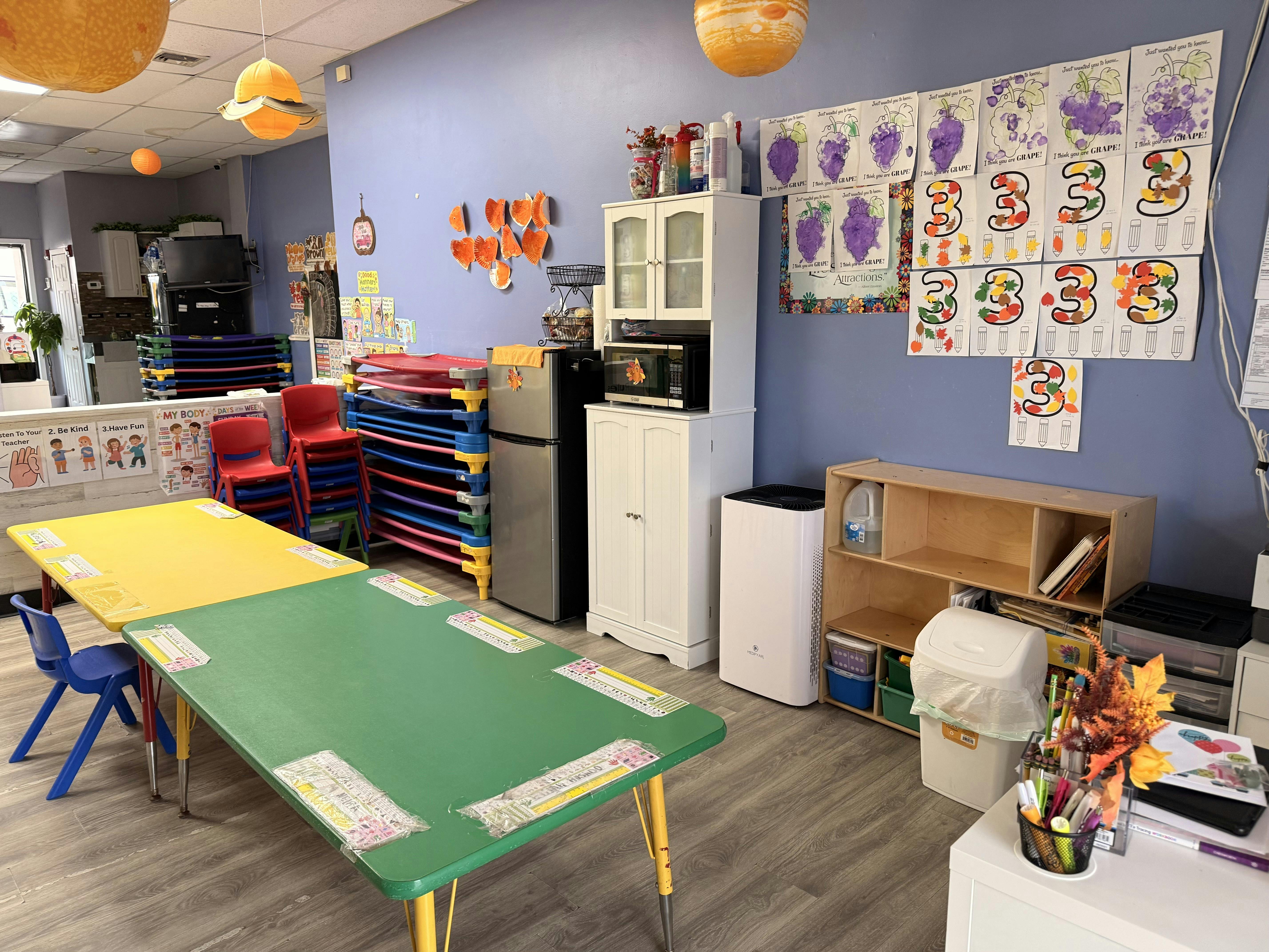 Classroom with tables, chairs, and children's artwork on the wall