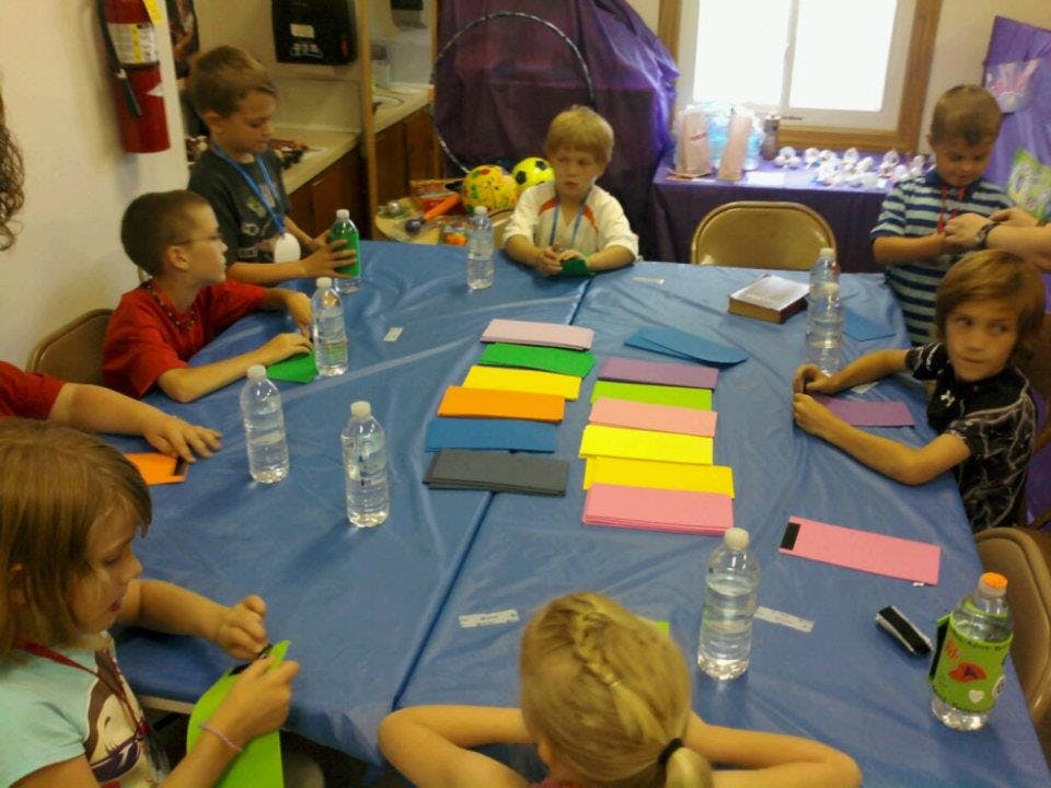 Children sitting around a table with colorful paper