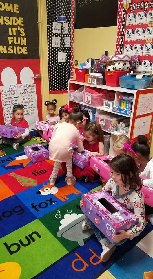 Children sitting on a colorful rug with decorated boxes