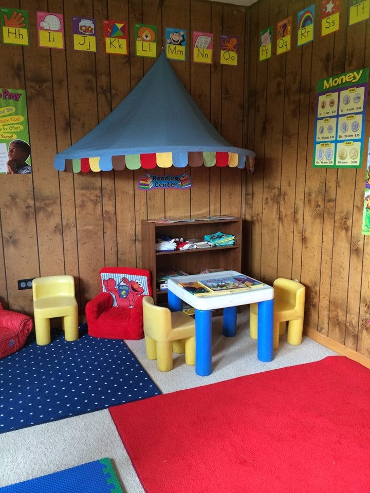 Children's play area with small table and chairs, toy shelf, and colorful rugs
