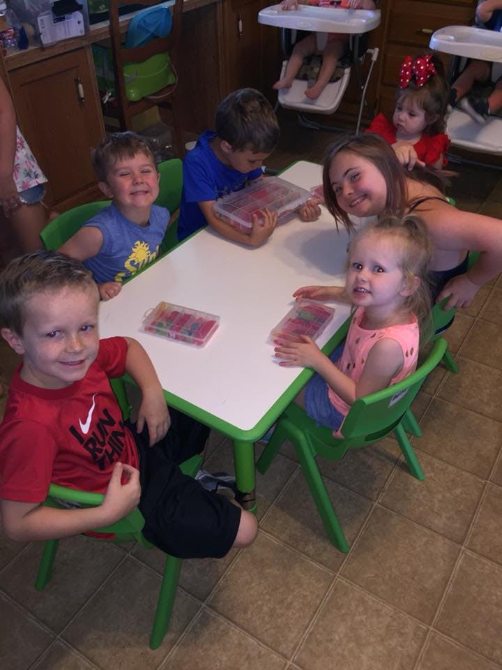 Children and a person sitting around a table with containers