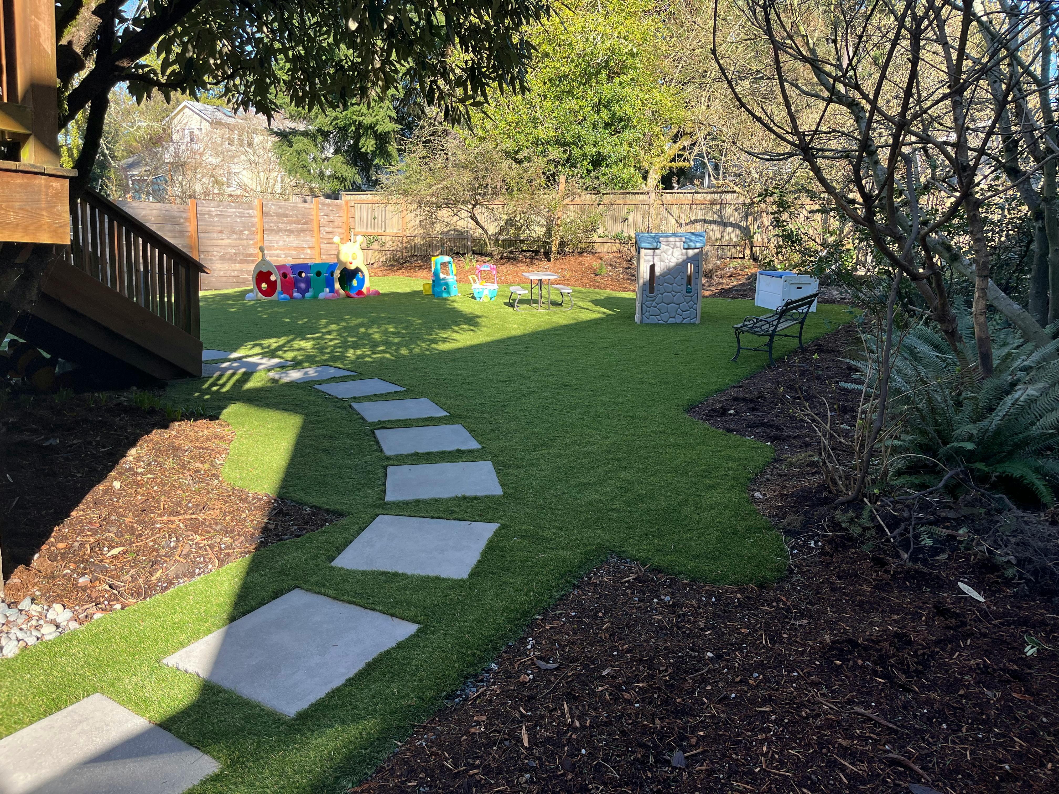 Backyard with a stone path, green lawn, and play structures
