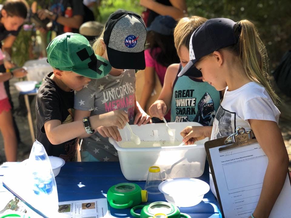 Children participating in an outdoor activity with tubs of water