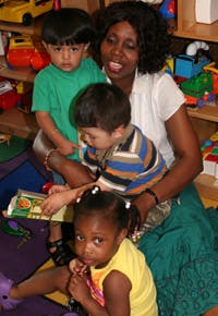 Adult with three children looking at a book