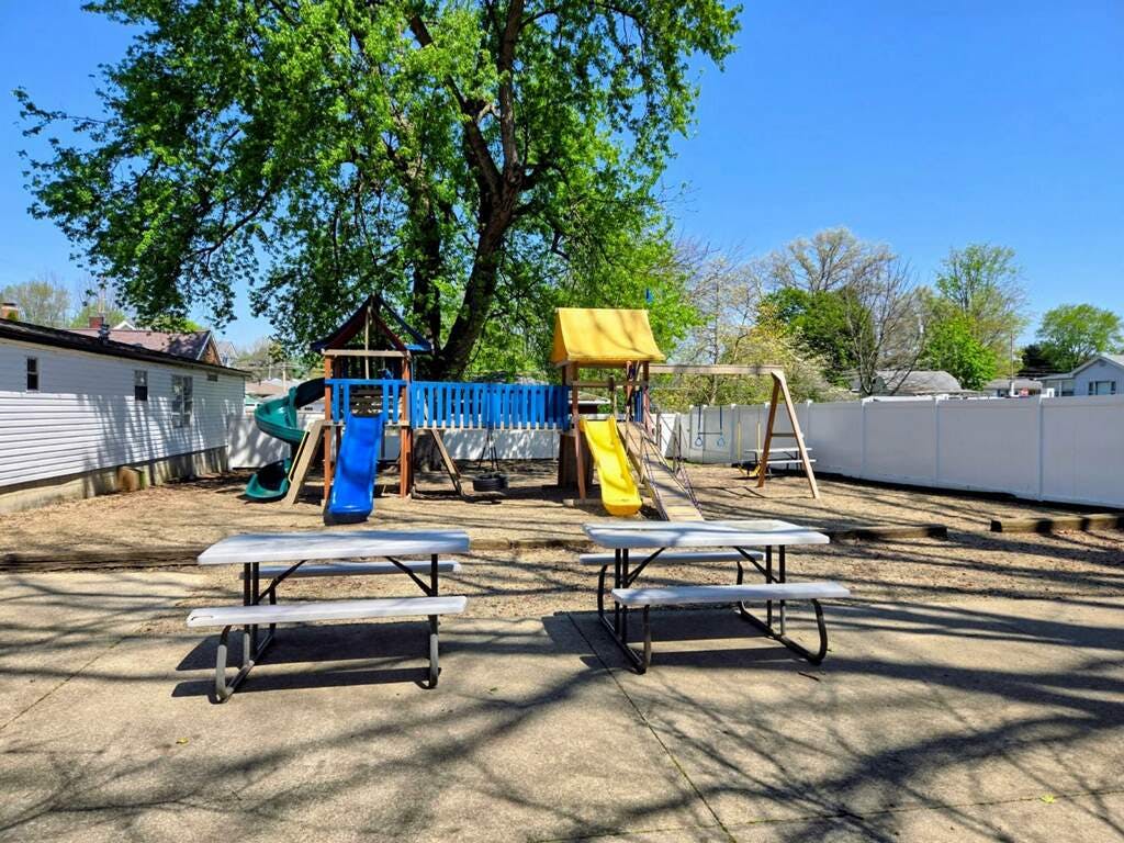 Playground equipment with slides and picnic tables in a backyard