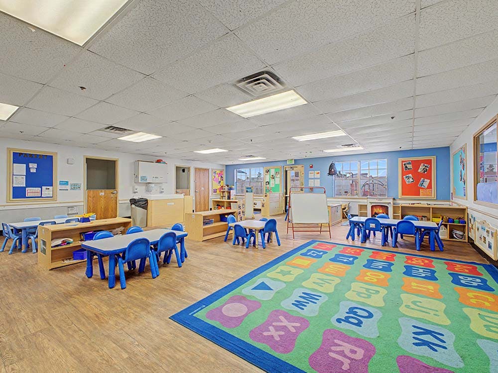 Empty colorful preschool classroom with small blue tables and chairs