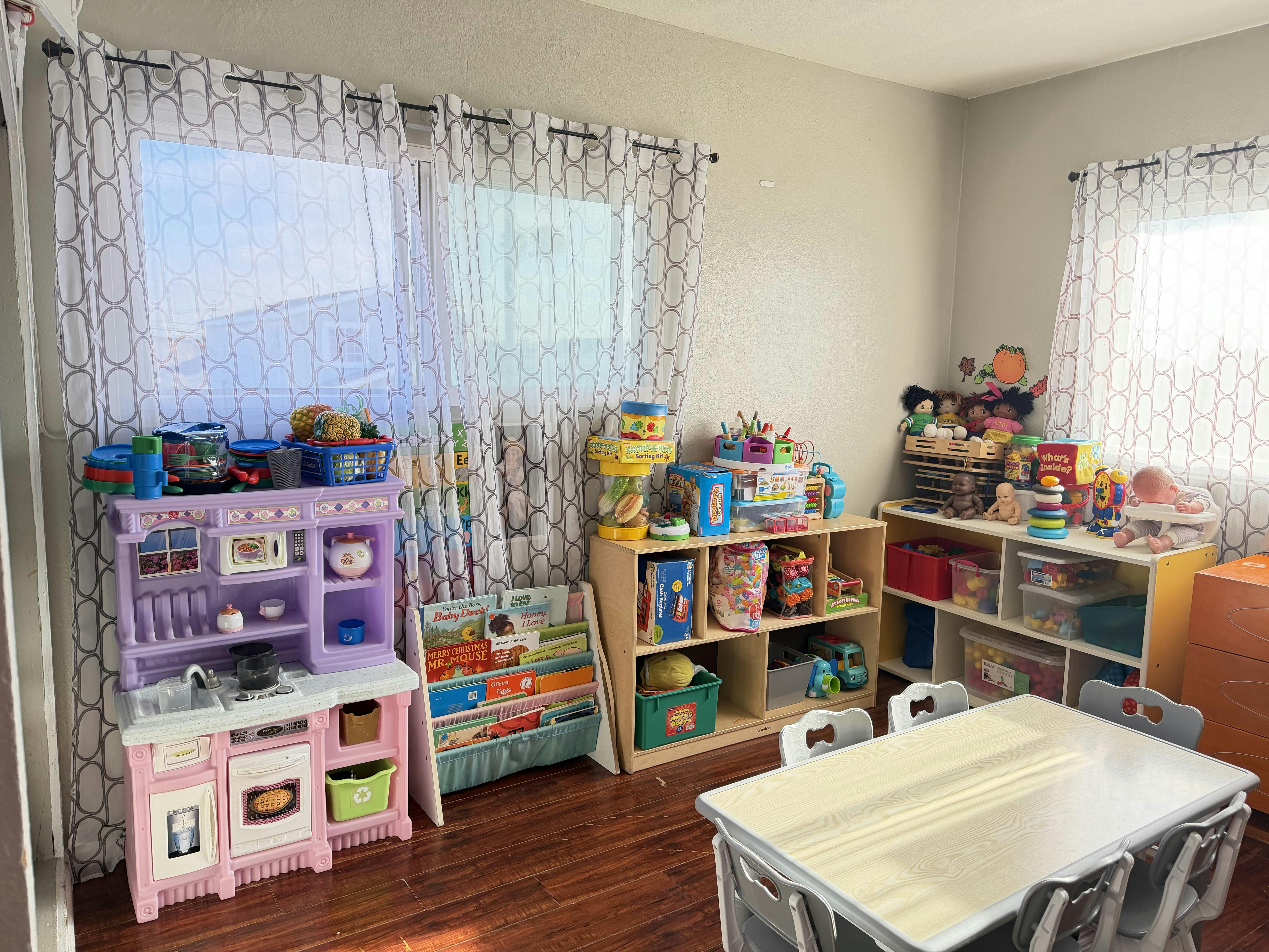 Child's playroom with toys, a toy kitchen, bookshelves, and a table with chairs