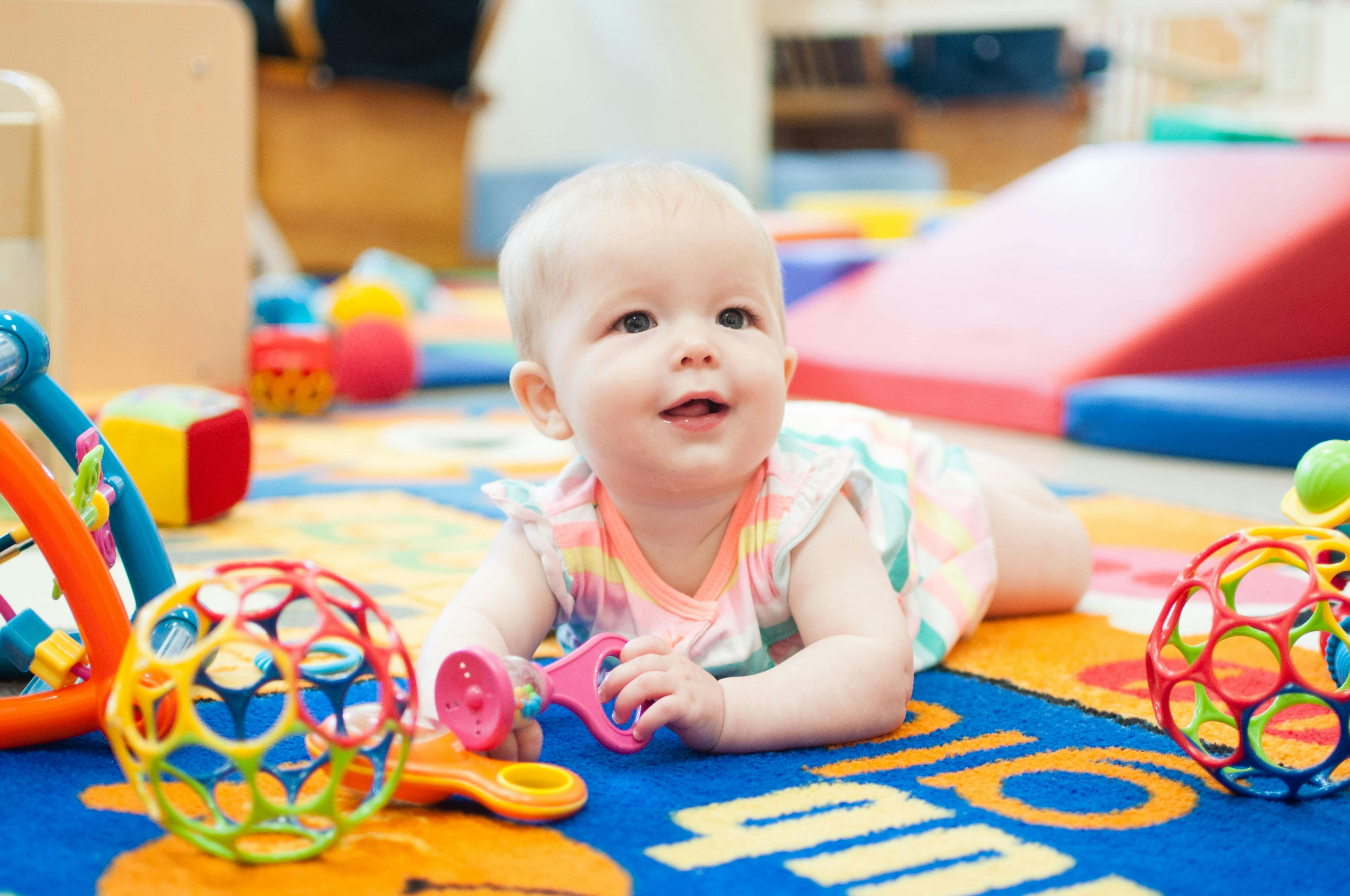Child on stomach on a colorful rug with toys