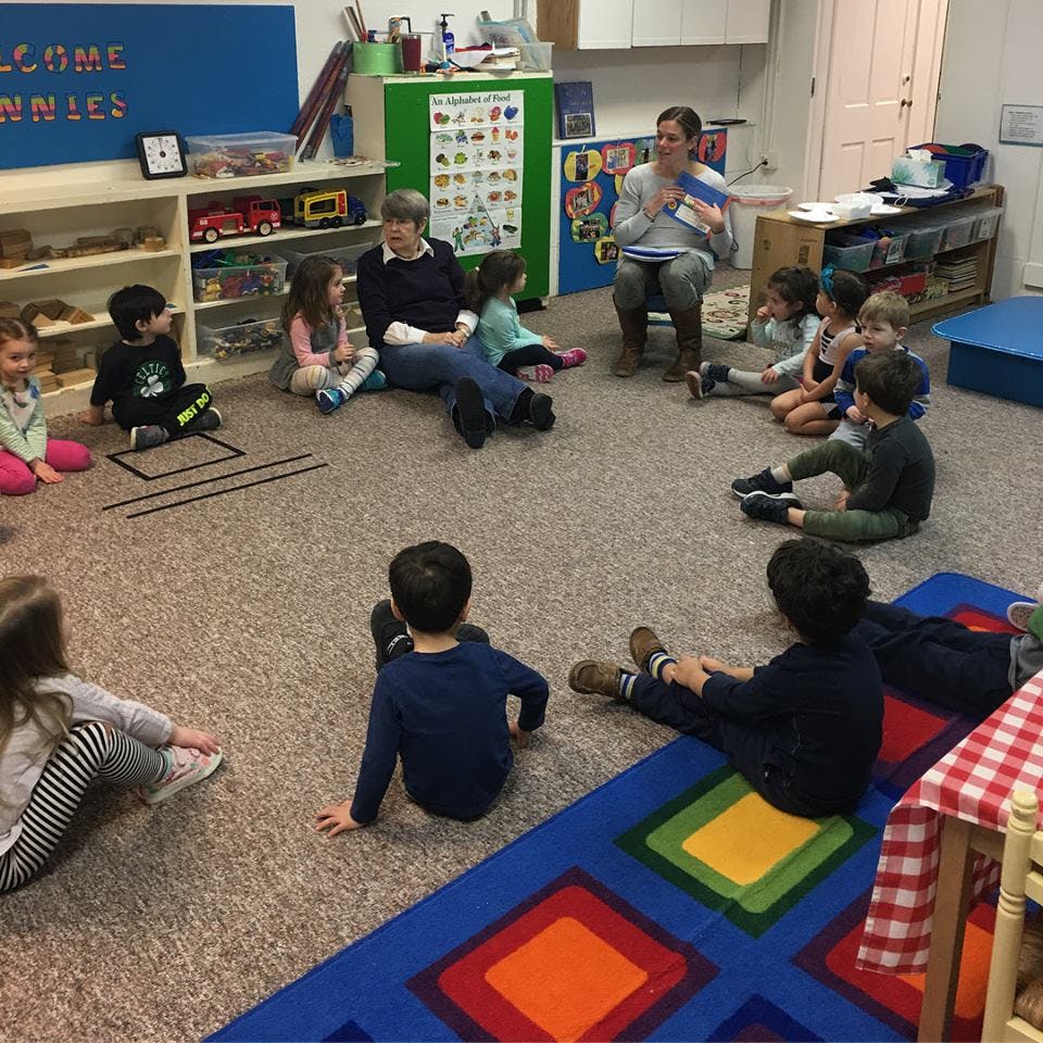 Adults and children sitting on the floor in a classroom