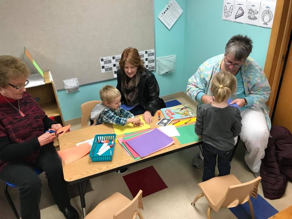 Adults and children at a table with craft supplies