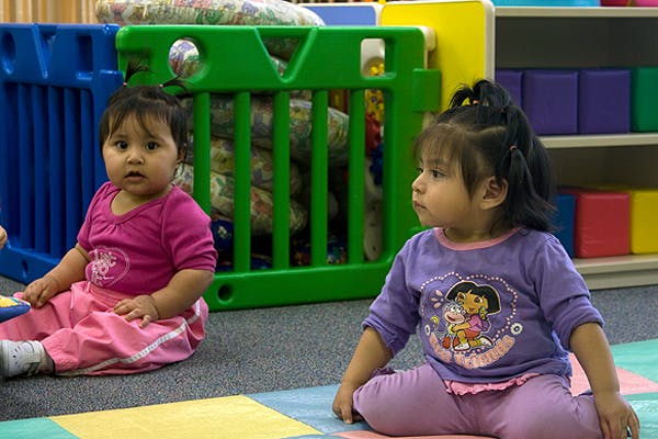 Two children sitting on a colorful mat in a play area
