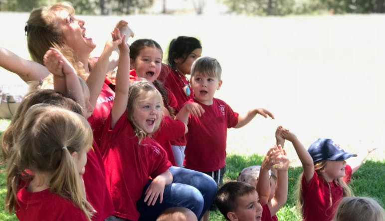 Adult and children in red shirts with arms raised