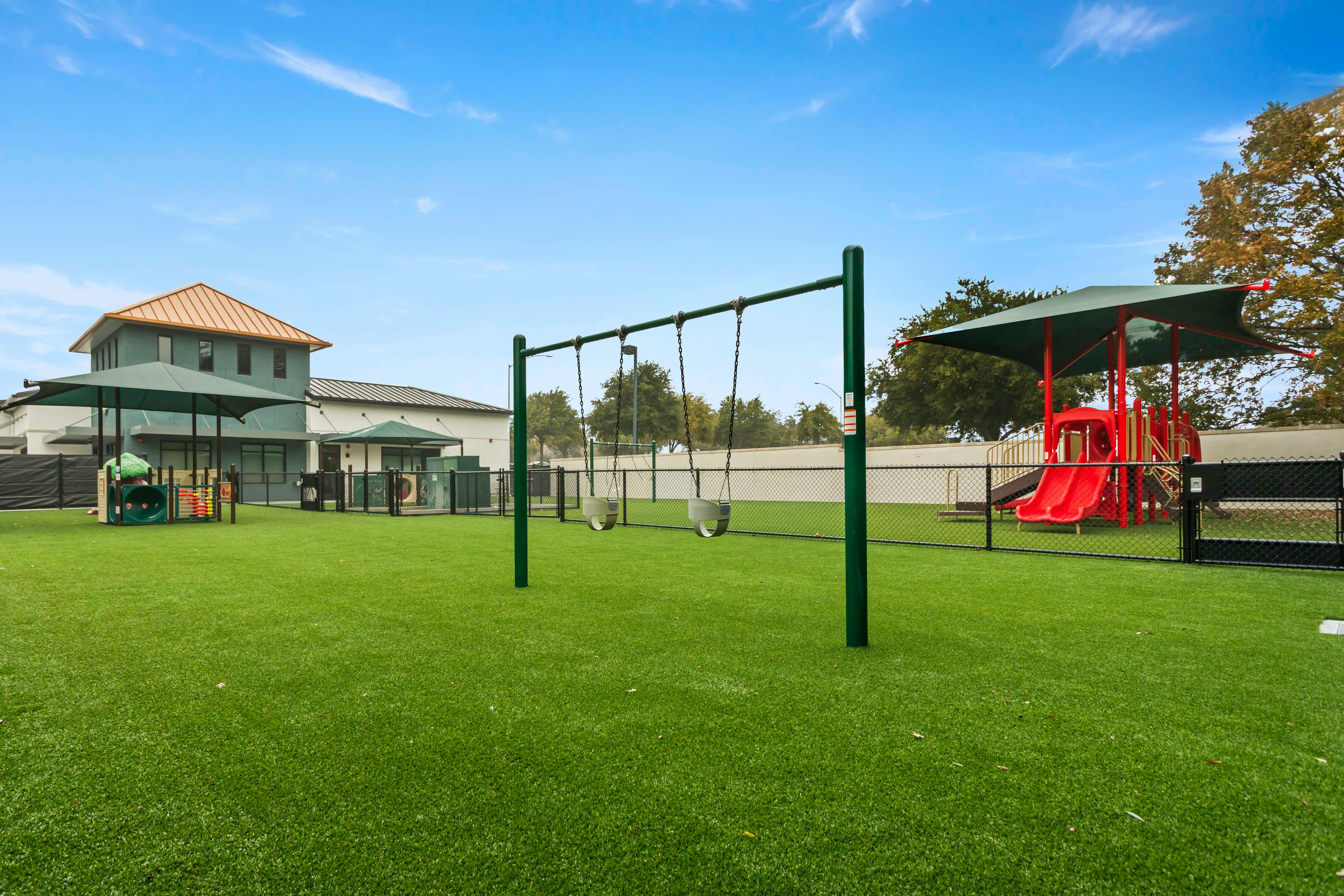 Playground with swings, slides, and play structures on artificial grass