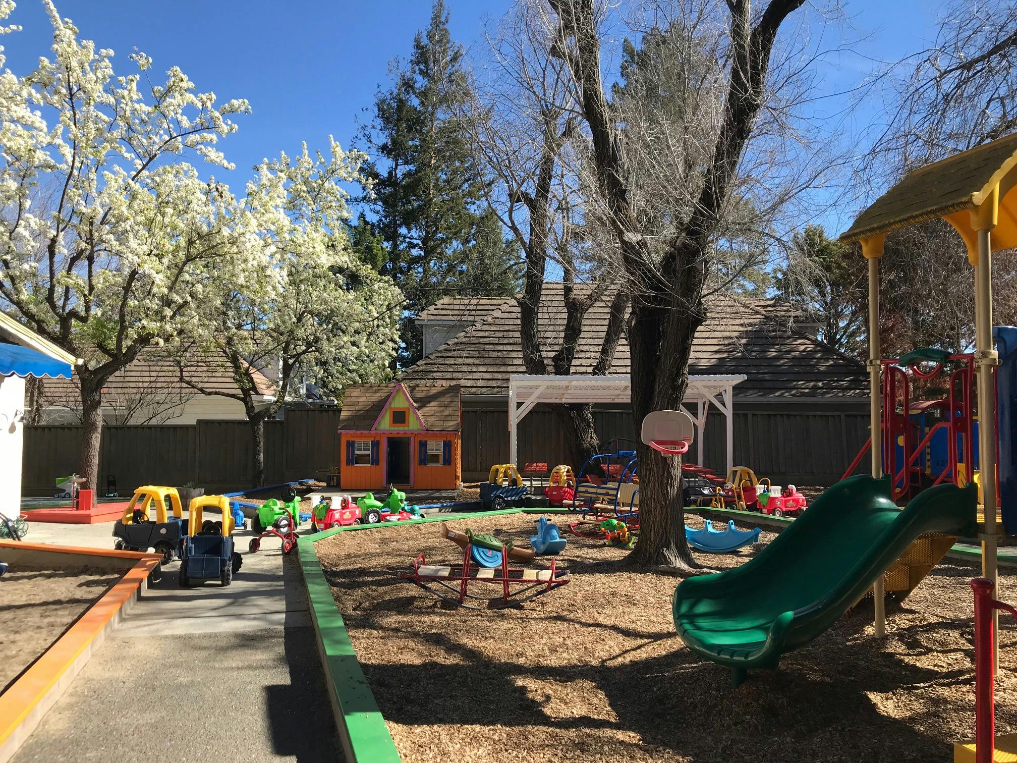 Outdoor playground with slide, playhouses, and ride-on toys